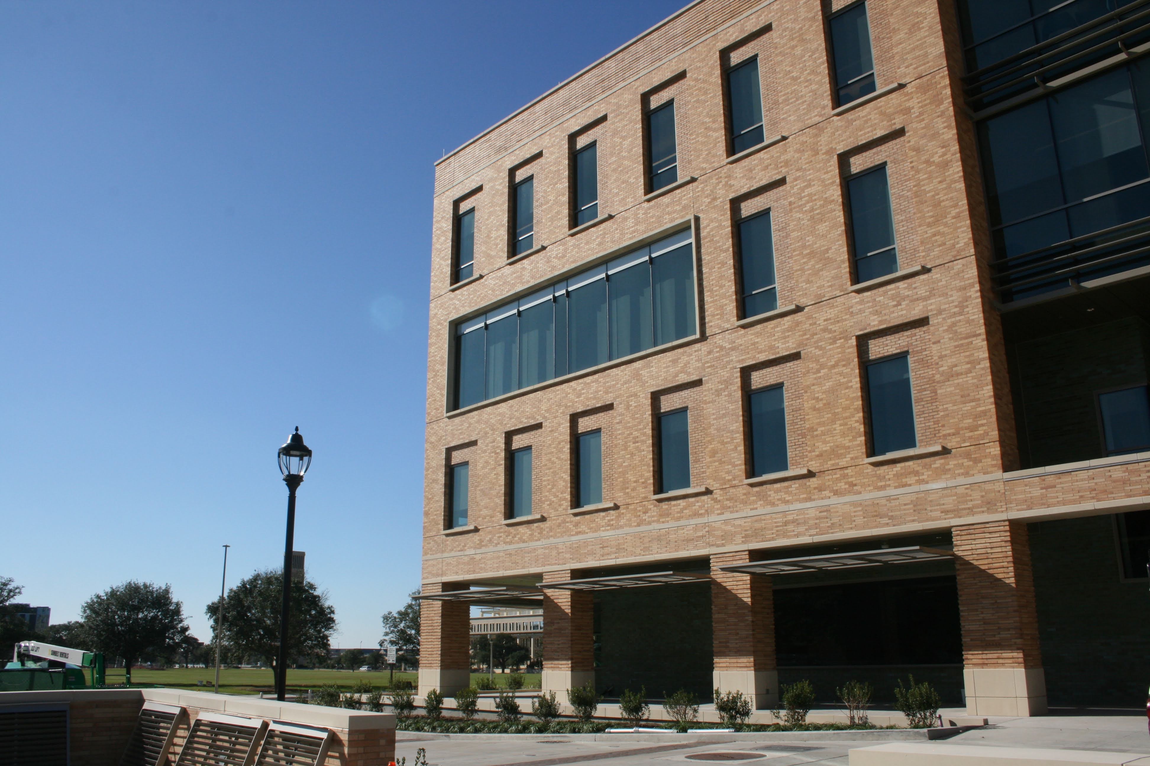 Texas A&M Student Services Building multi-story brick facade with ground-level colonnade and plaza seating area